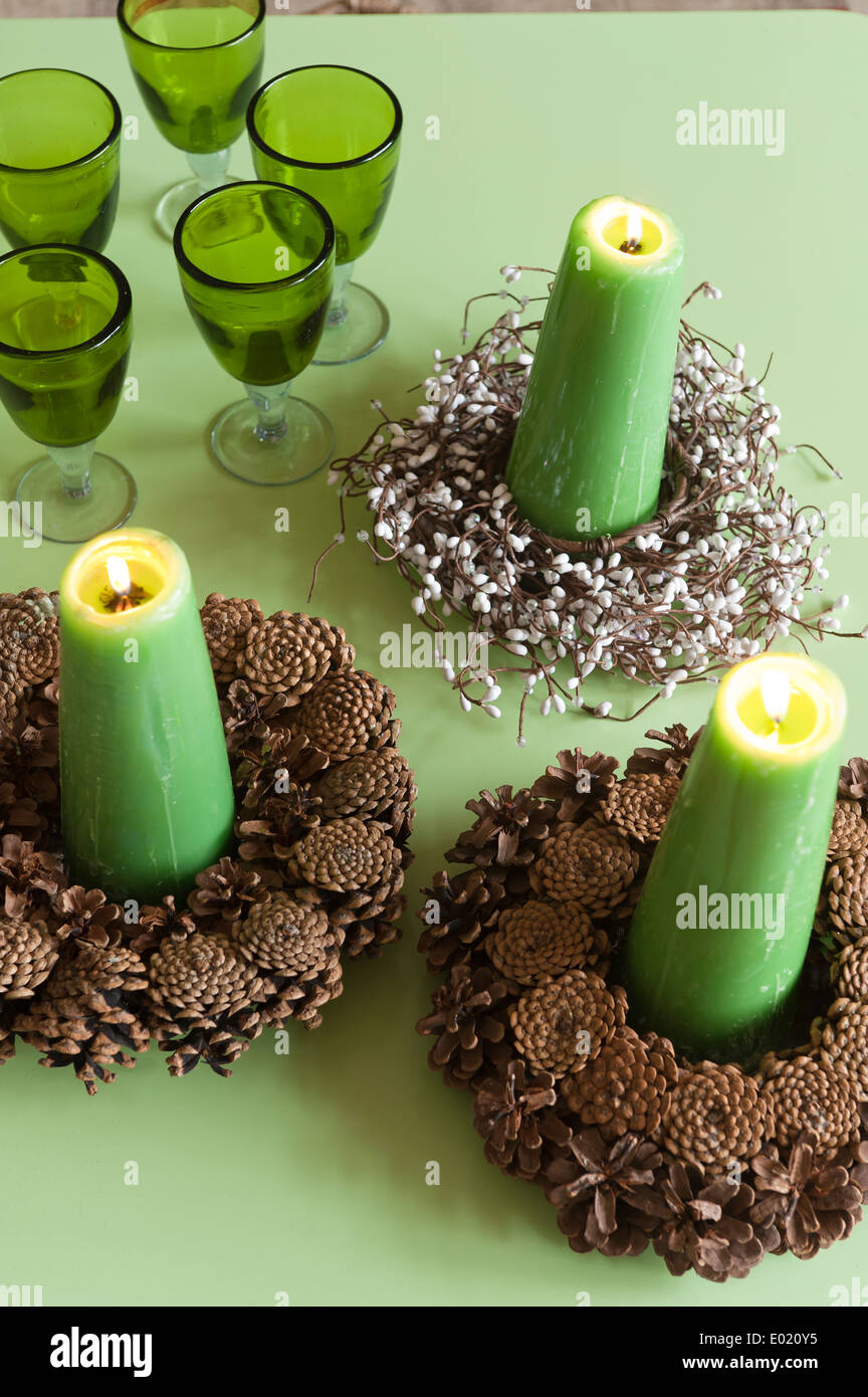 Grüne Kerzen Kegel Kerzenhalter auf grüne Tischplatte mit grünem Glas Stockfoto