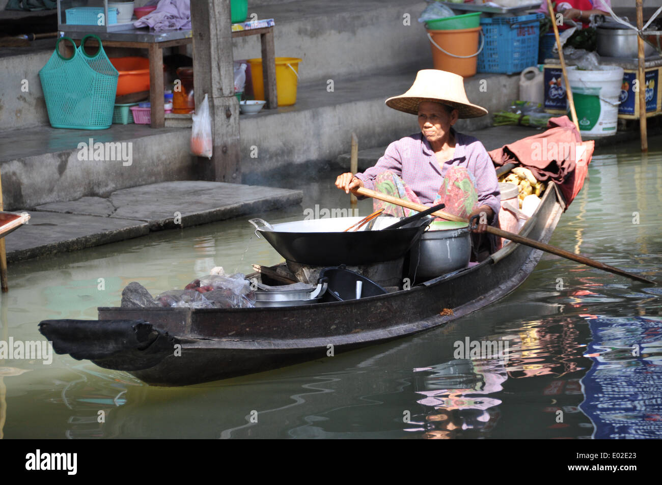 Thai-Frau mit Kochutensilien paddeln ein Boot auf einem schwimmenden Markt. Stockfoto