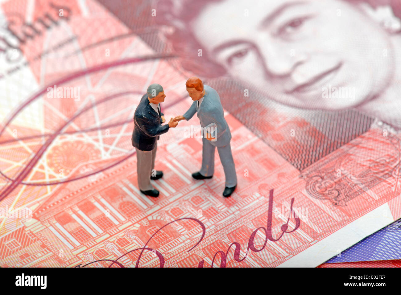 Manager, schüttelt Hände, Miniatur-Figuren auf einer britischen Pfund Sterling-Banknote, symbolisches Bild für Unternehmen Stockfoto