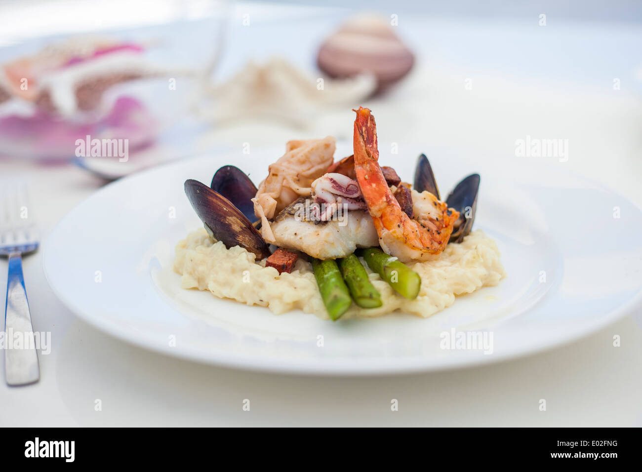 Gemischte Meeresfrüchte Gericht mit Muskeln, Garnelen und Tintenfisch auf einem Bett aus Polenta und grüne Bohnen. Schuss auf eine Superyacht aufgenommen. Stockfoto