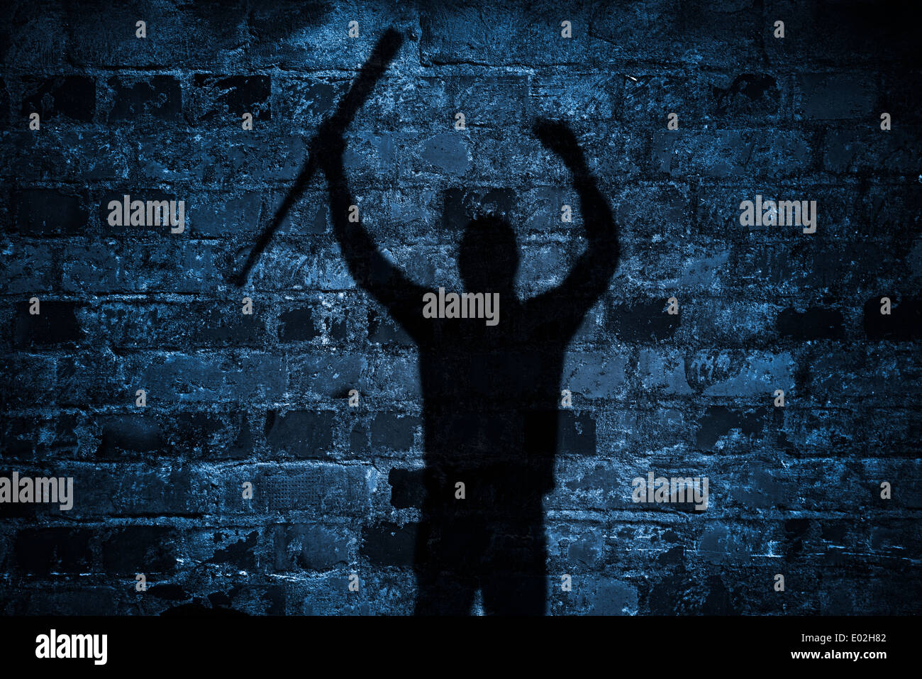 Schatten der Demonstrant mit Baseballschläger und erhobenen Armen auf Mauer in der Nacht Stockfoto