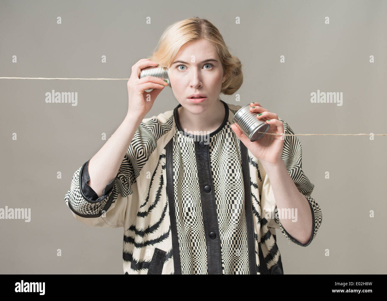Blonde Frau mit Blechdose Telefon. Konzeptbild von Verbindung und Kommunikation. Stockfoto
