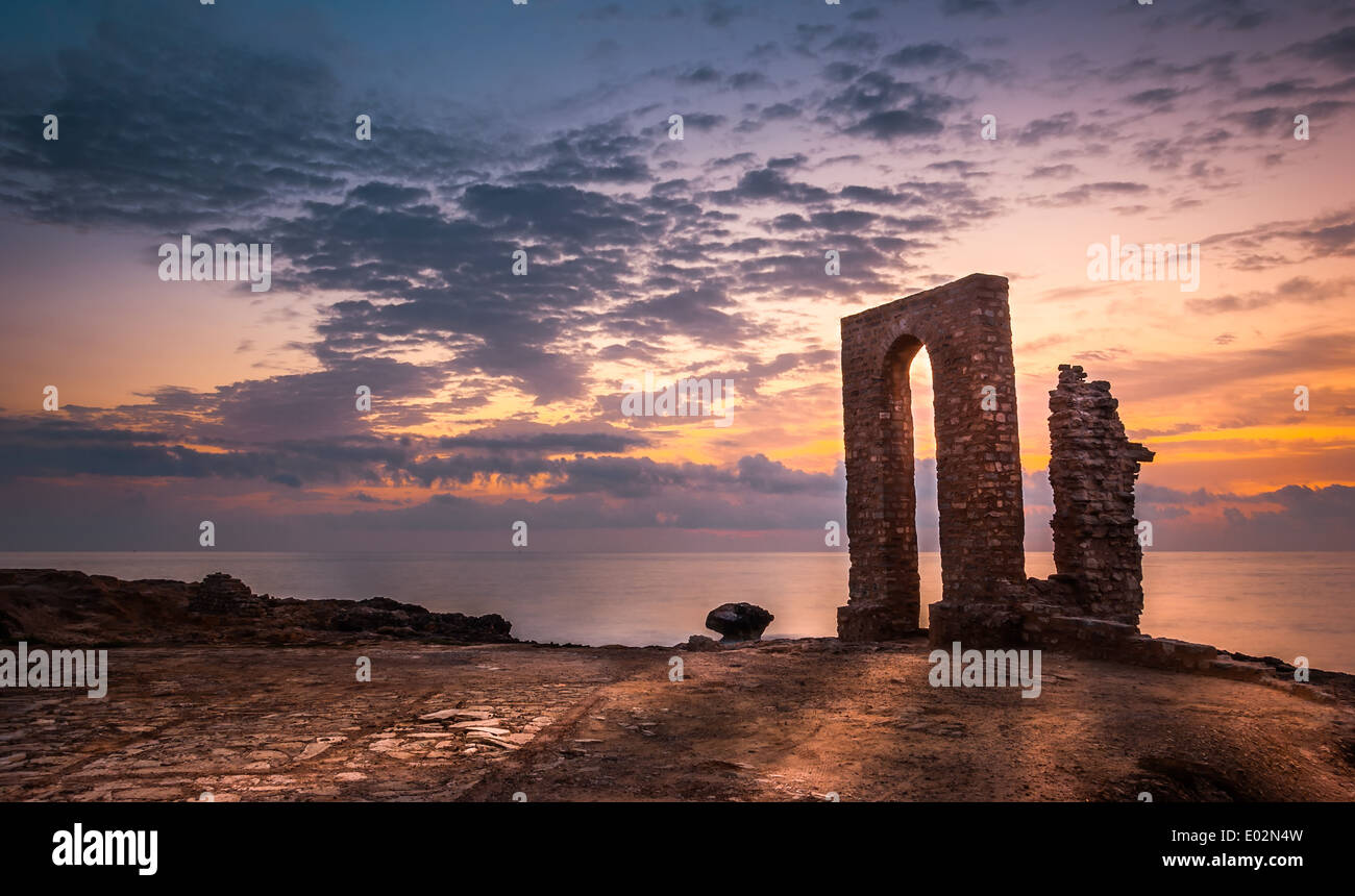 Sonnenuntergang über dem Meer und felsigen Küste mit antiken Ruinen und Tor nach Afrika in Mahdia, Tunesien Stockfoto
