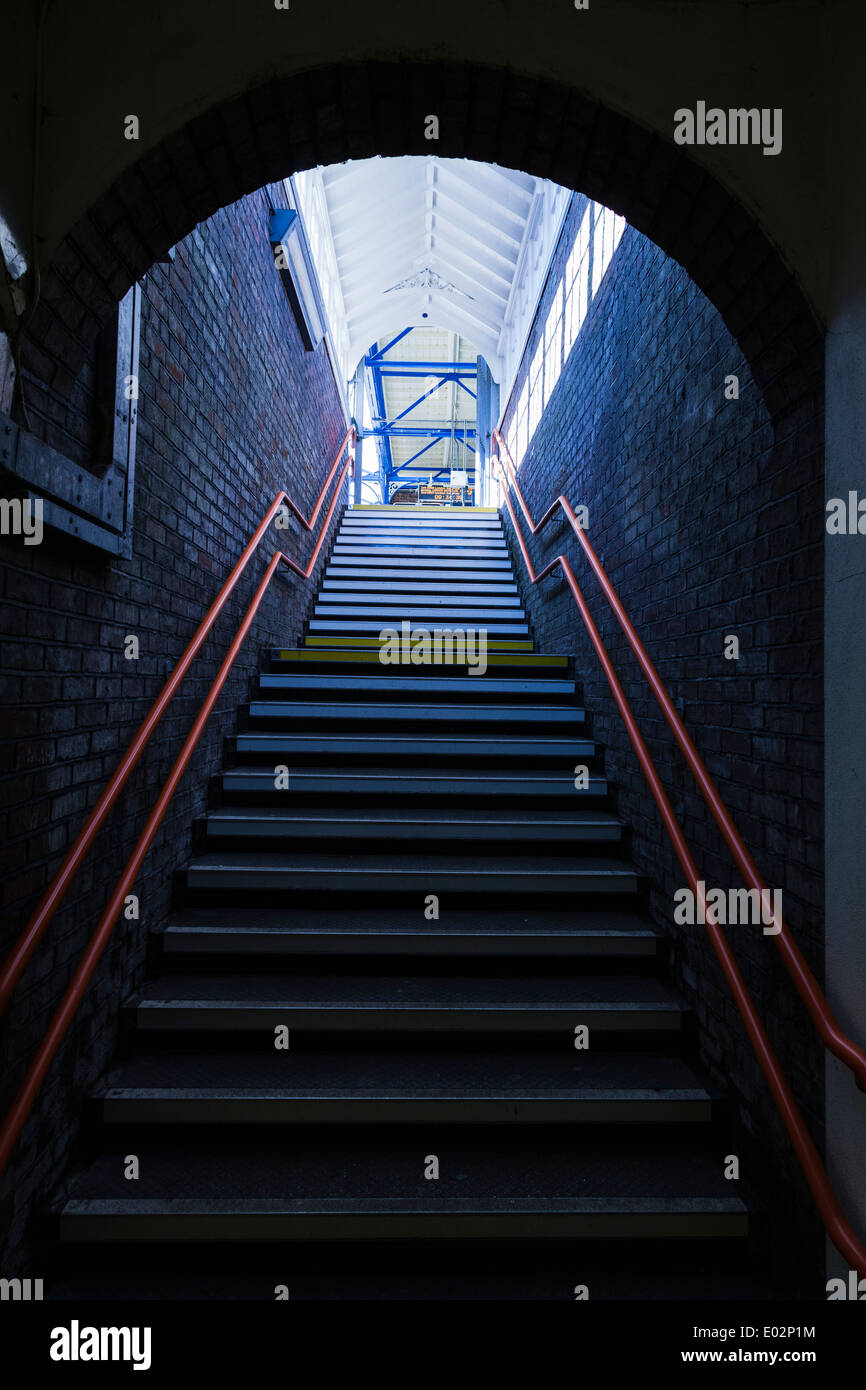 Stufen führen von dunkel ans Licht mit roten Handlauf. Stockfoto