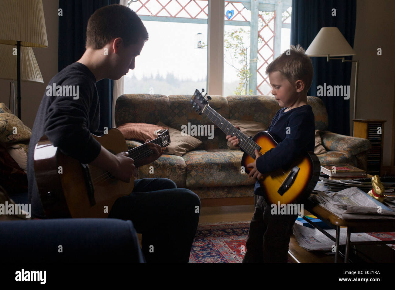 Ein 16 Jahre alten Teenager und seine 4 jährige Cousine spielen Gitarre zusammen in der Familie Wohnzimmer. Stockfoto