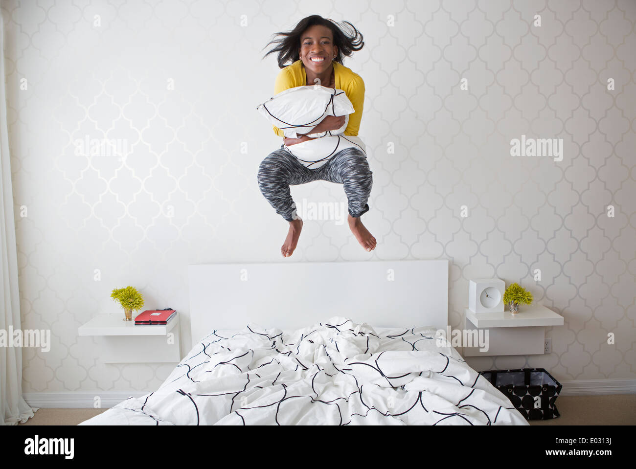 Ein junges Mädchen springen hoch in der Luft über dem Bett. Stockfoto