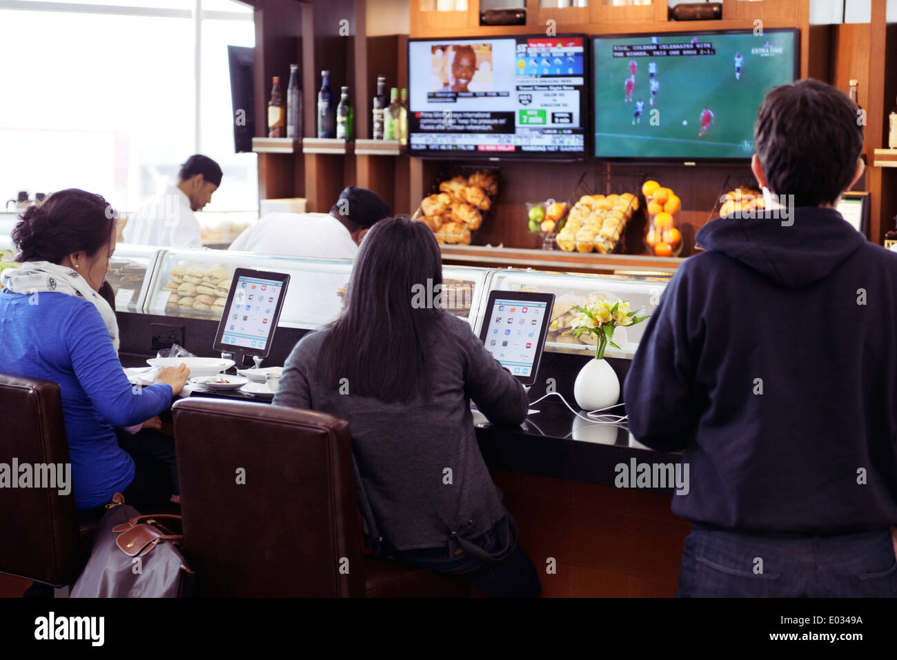 Menschen sitzen an einem Café-Schalter mit iPads vor ihnen. Toronto Pearson International Airport. Stockfoto
