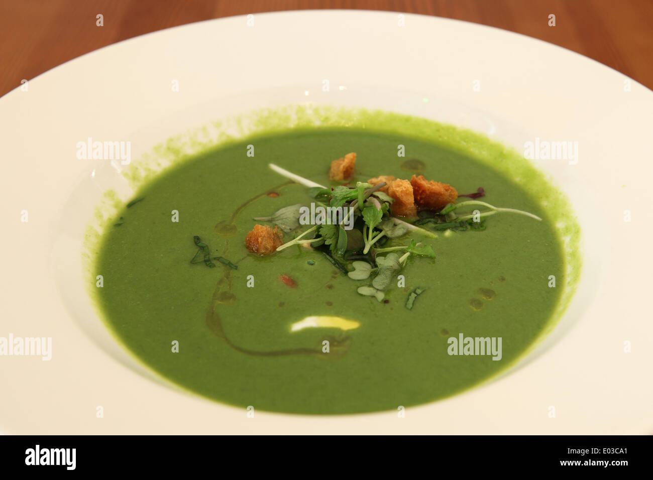 Eine moderne estnische Mahlzeit grüne Erbse Suppe mit Öl beträufelt und mit Croutons und Salat gestreut. Stockfoto