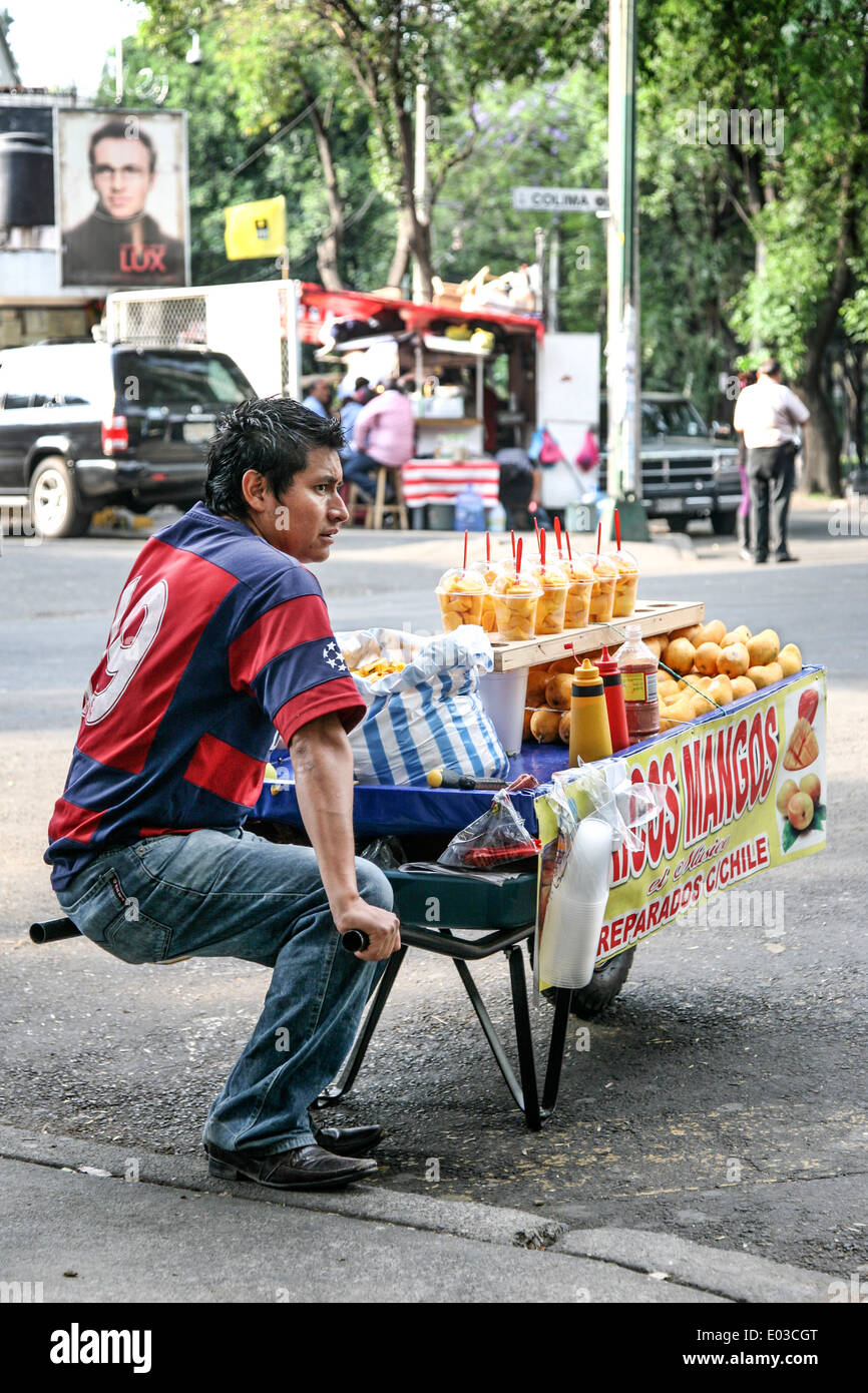 junger Mann im Fußball Shirt verkaufen frische Mangos & Container cubed Mangos, gewürzt mit Chili aus Schubkarre im Roma-Viertel DF Stockfoto