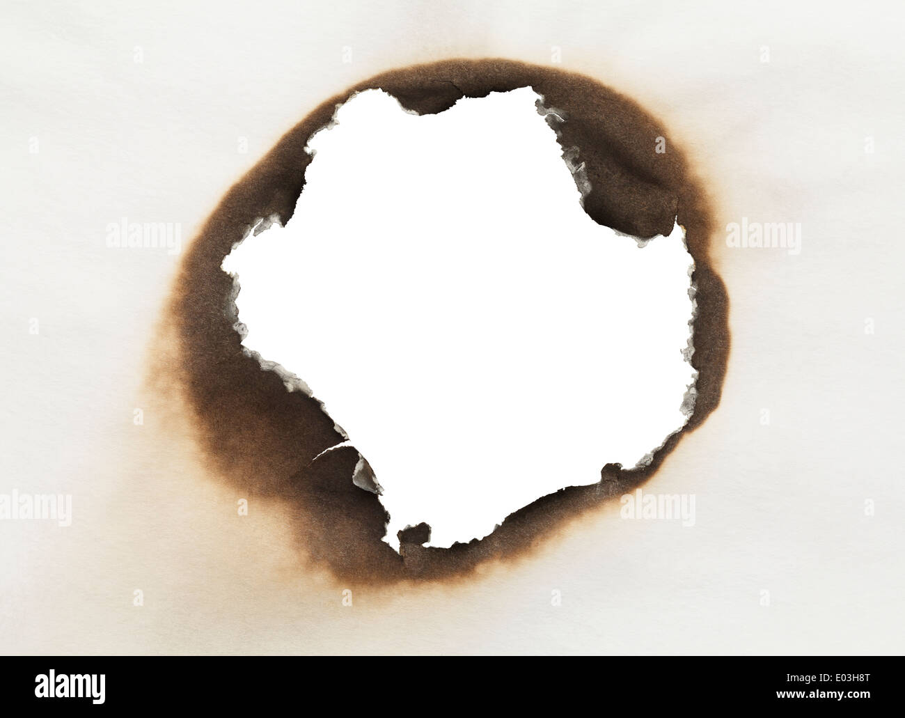Stück Papier mit verbrannten Loch in Kreisform mit weißem Hintergrund. Stockfoto