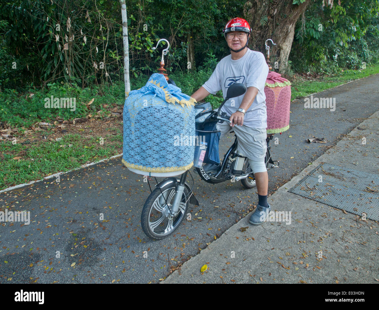 Ältere Mann mit Vögel in Käfigen auf seinem Fahrrad in Singapur Stockfoto