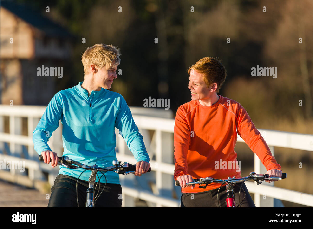 Zwei Frauen zusammen Radfahren entlang der Brücke bei Sonnenaufgang Stockfoto