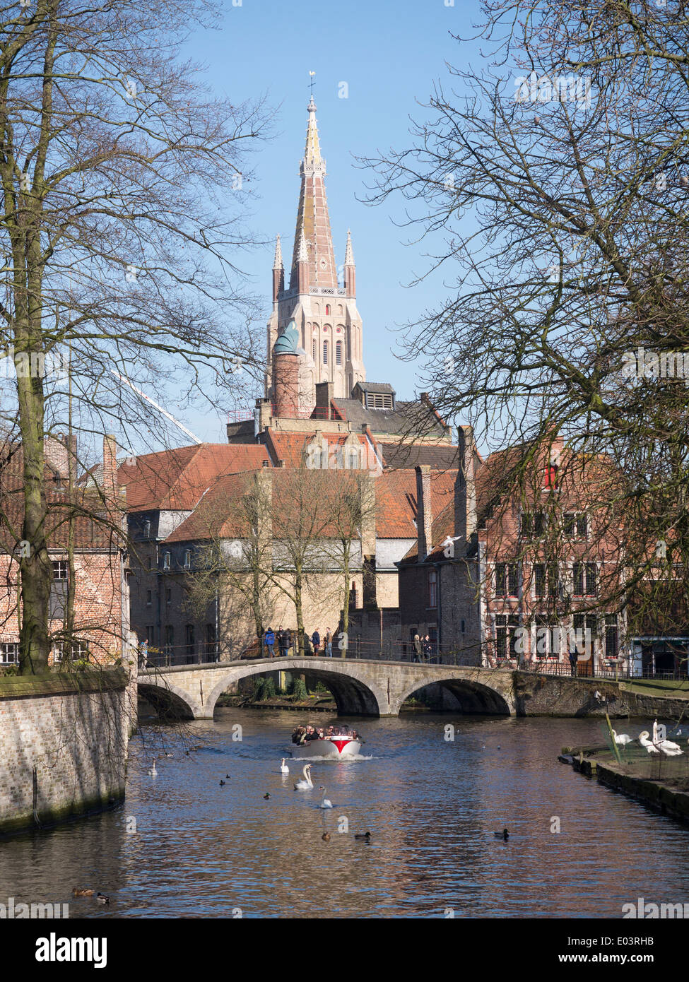 Ein Blick von Begijnhof, Brügge, Belgien, in Richtung der Liebfrauenkirche mit Touristenboot nähert sich Stockfoto