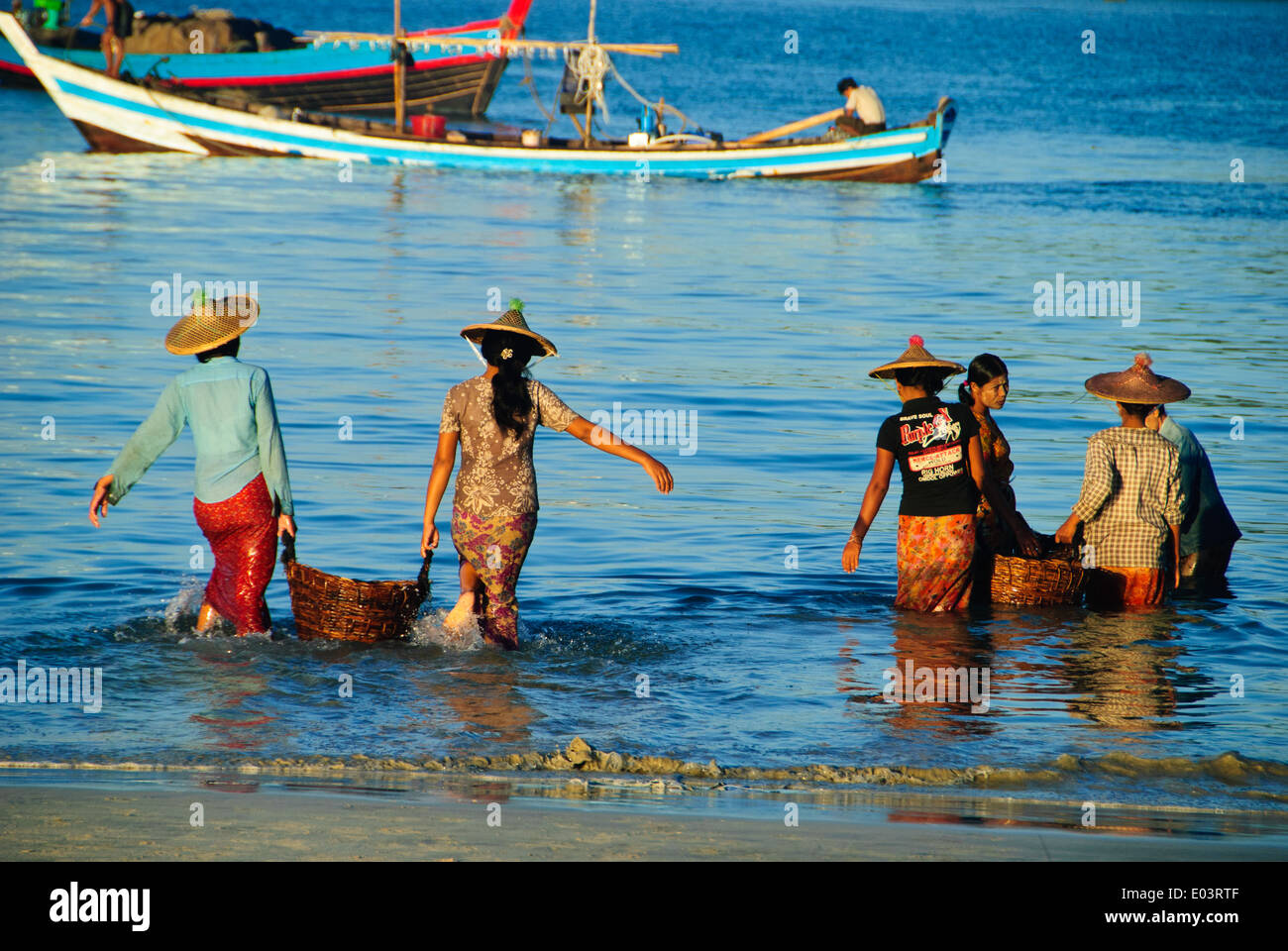 Birmanischen Frauen, die die Fische vom Boot an den Strand vor einem Fischerdorf Stockfoto