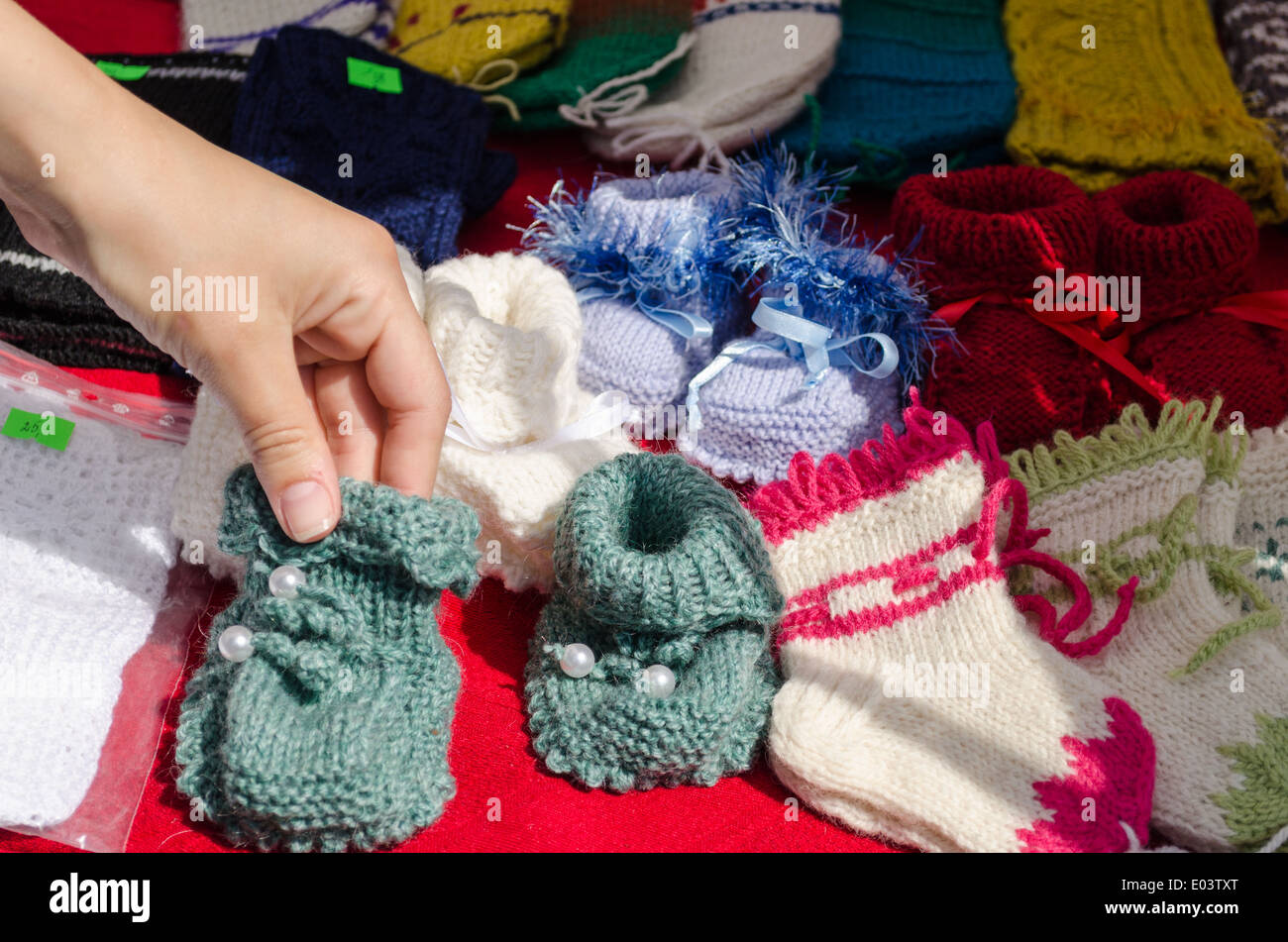 Hand nehmen bunte hausgemachte Wolle handgestrickte gestrickte warme gemütliche Babyschuhe verkauft Markt fair. Stockfoto