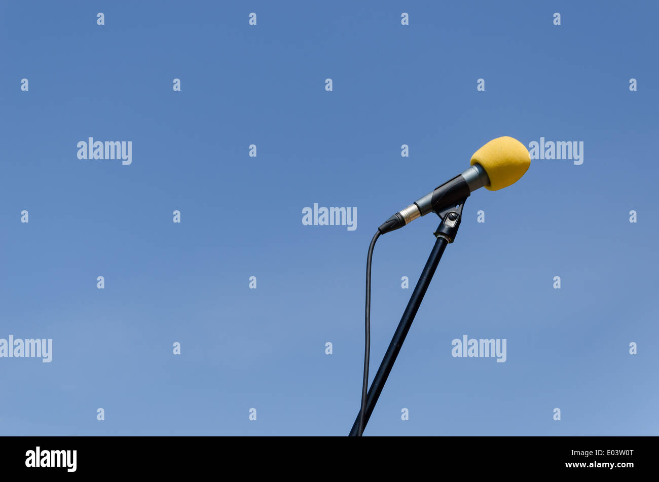 gelbe Mikrofon mit Ständer auf blauen Himmelshintergrund Stockfoto