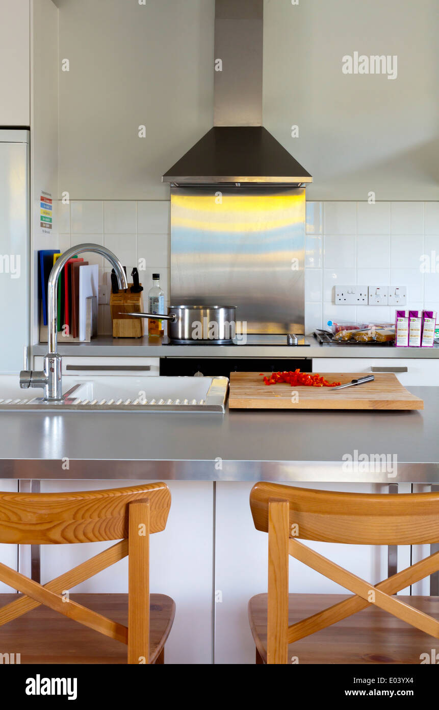 Moderne Küche Interieur mit Herd und Spültisch Edelstahl Dunstabzugshaube  und Holzstühlen vor Frühstücksbar Stockfotografie - Alamy