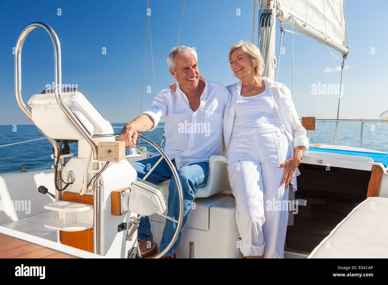 Ein glückliches senior paar lachen, haben Spaß am Steuer eine Yacht oder ein Segel Boot auf einem ruhigen blauen Meer segeln Stockfoto