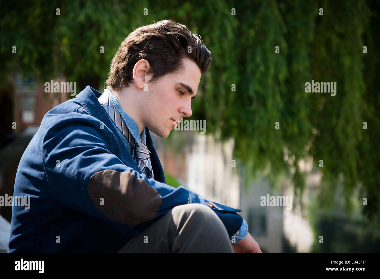 Traurig, besorgt junger Mann sitzt im Freien in der Stadt, auf der Suche nach unten Stockfoto