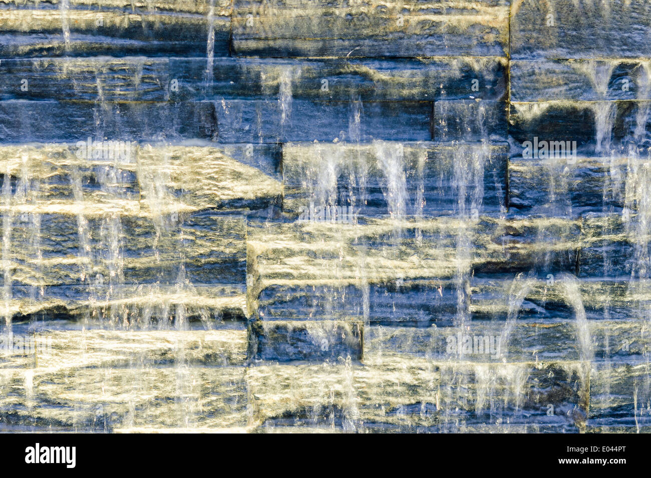 Fließendes Wasser über dunkle Steinmauer mit spot-Beleuchtung Stockfoto