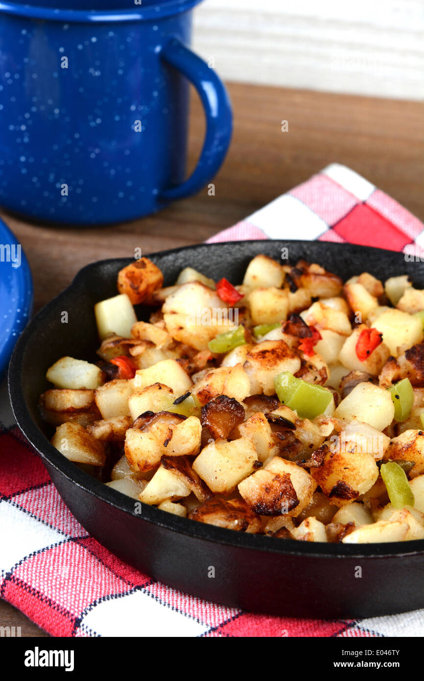 Nahaufnahme einer gusseisernen Pfanne voller Frühstück Kartoffeln. Hochformat mit geringen Schärfentiefe. Stockfoto