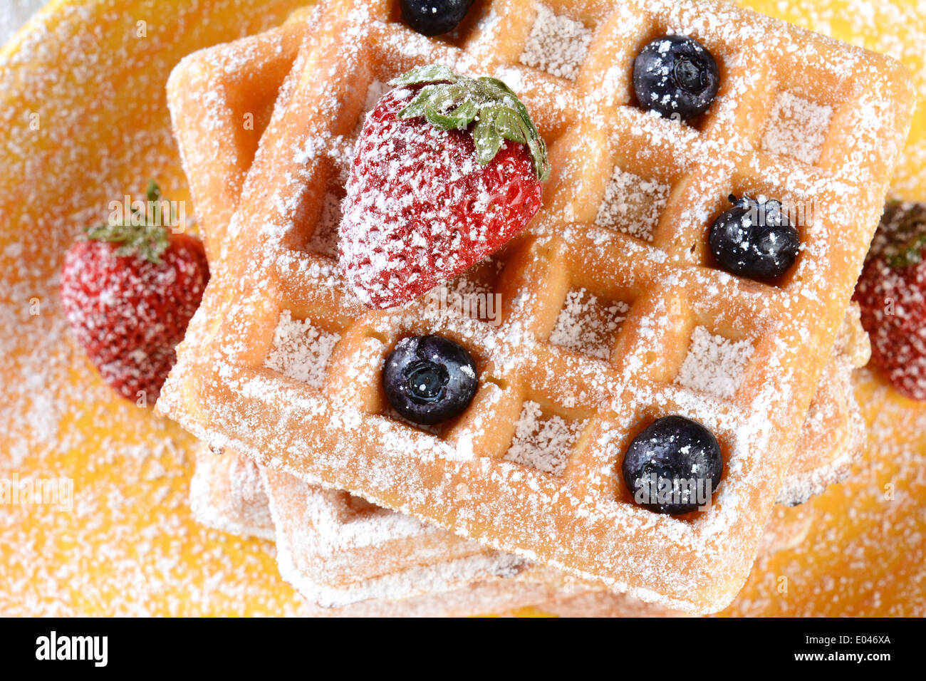 Nahaufnahme von fruchtigen Waffeln mit Puderzucker bedeckt. Frische Heidelbeeren und Erdbeeren auf einen Stapel von belgischen Stil Waffeln Stockfoto