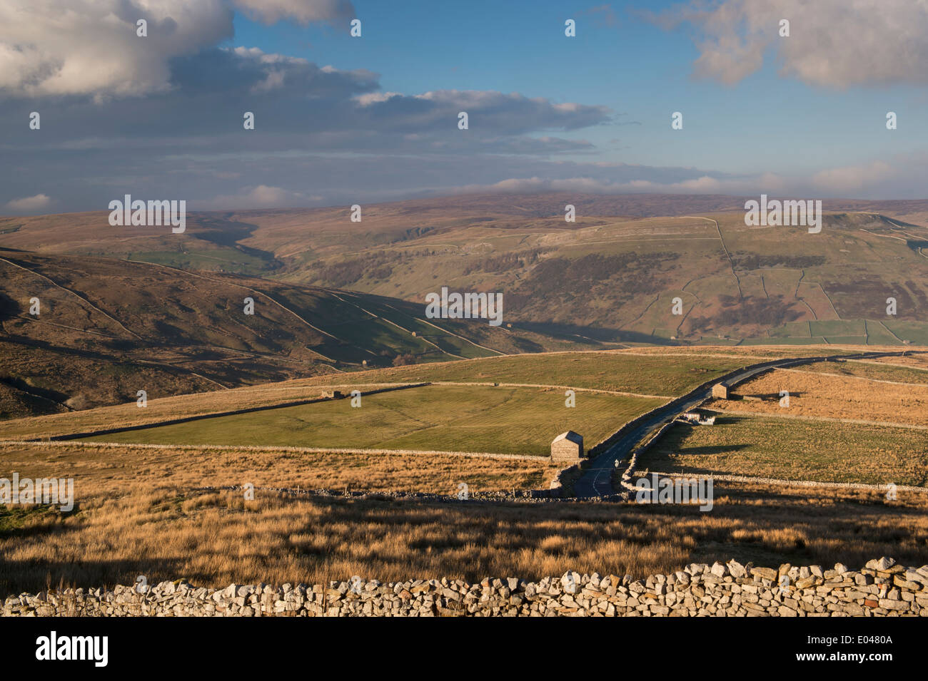 Blick über den Butterwbs Pass (landschaftlich reizvolle Straßenroute über sanfte Hügel und Hochmoore, vorbei an verlassenen, sonnenbeschienenen Scheunen) - Yorkshire Dales, England. Stockfoto