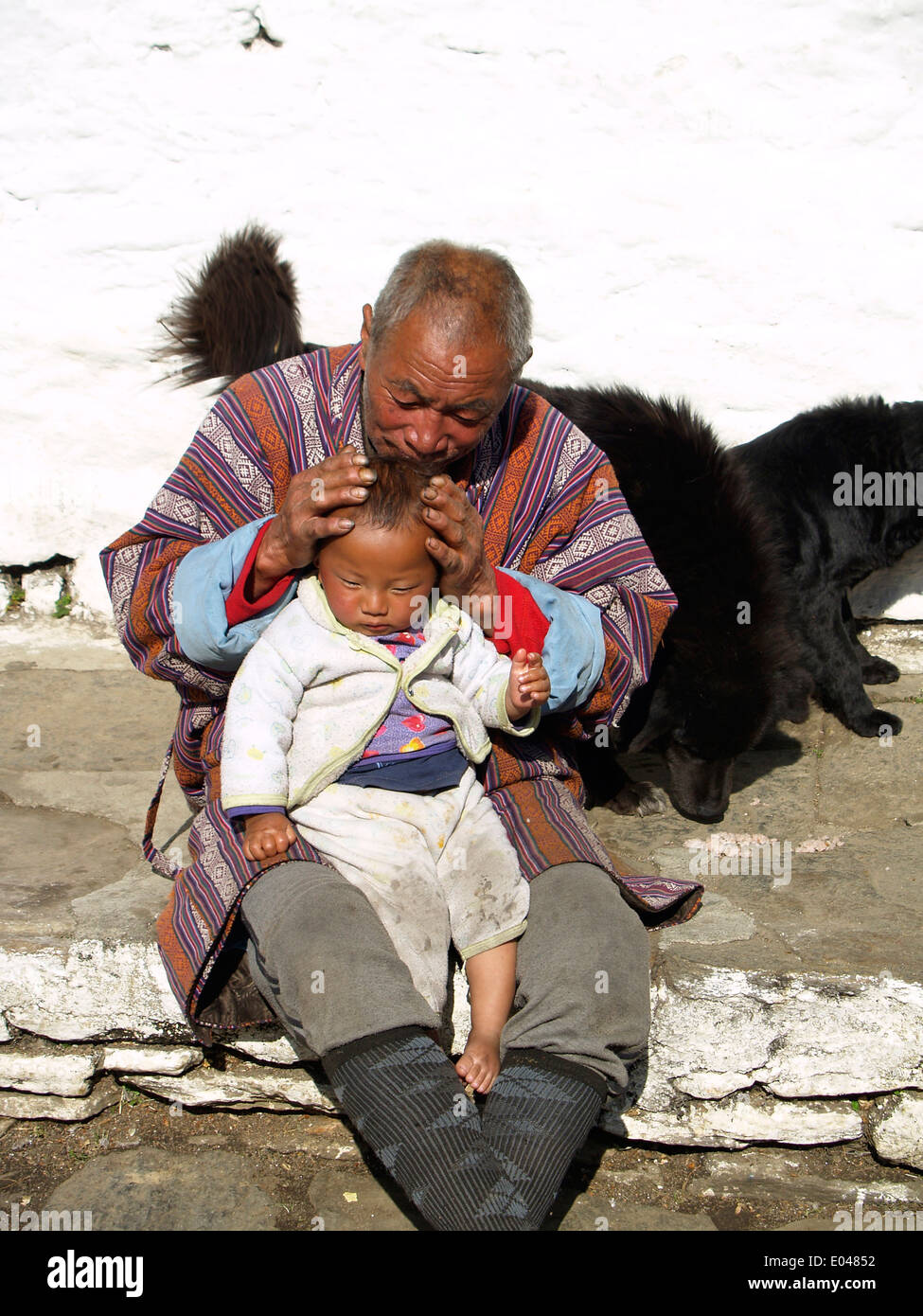 Ein bhutanischer Großvater hält sein Enkel im Kichu Kloster in Paro, Bhutan Stockfoto