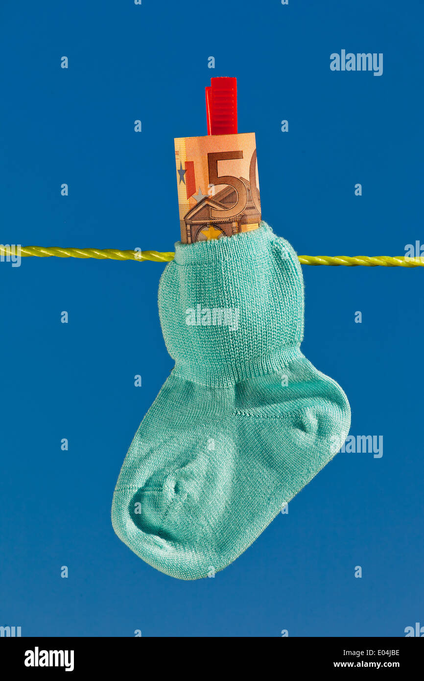 Baby Socken auf der Wäscheleine mit Eurobank Noten. Blauer Himmel., Baby Socken Auf Waescheleine Mit Eurogeldscheinen. Blauer Himmel. Stockfoto