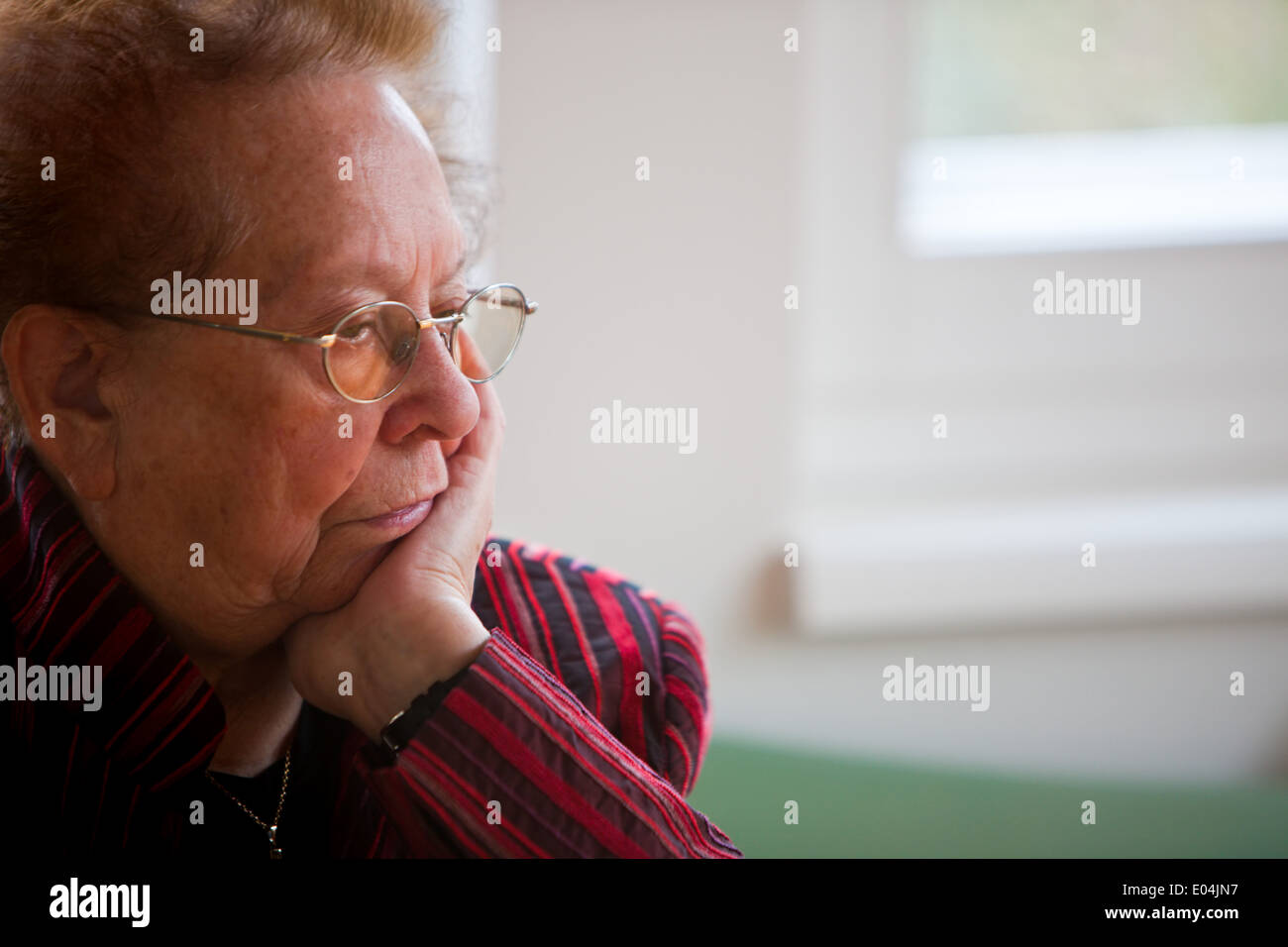 Eine Alte Frau Sitzt Nachdenklich bin in alte Frau sitzt nachdenklich am Fenster Fenster Stockfoto