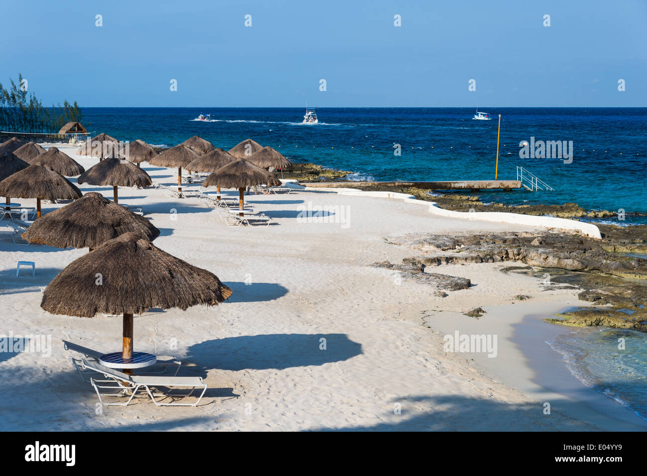 Strohgedeckte Sonnenschirme verstreut auf einem Beach Resort. Cozumel, Mexiko. Stockfoto