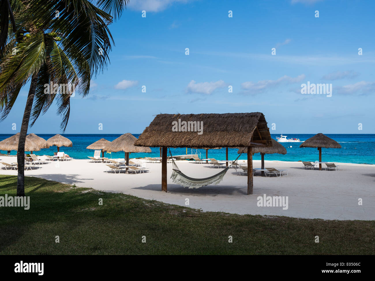 Strohgedeckte Hütte und Sonnenschirme verstreut auf einem Beach Resort. Cozumel, Mexiko. Stockfoto