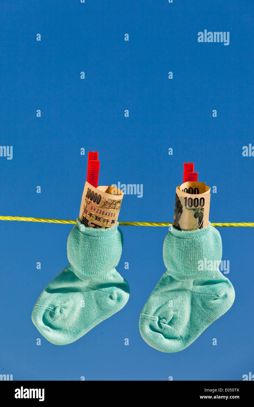 Baby Socken auf der Wäscheleine mit Yen Banknoten aus Japan., Baby Socken Auf Waescheleine Mit Yen Geldscheinen aus Japan. Stockfoto