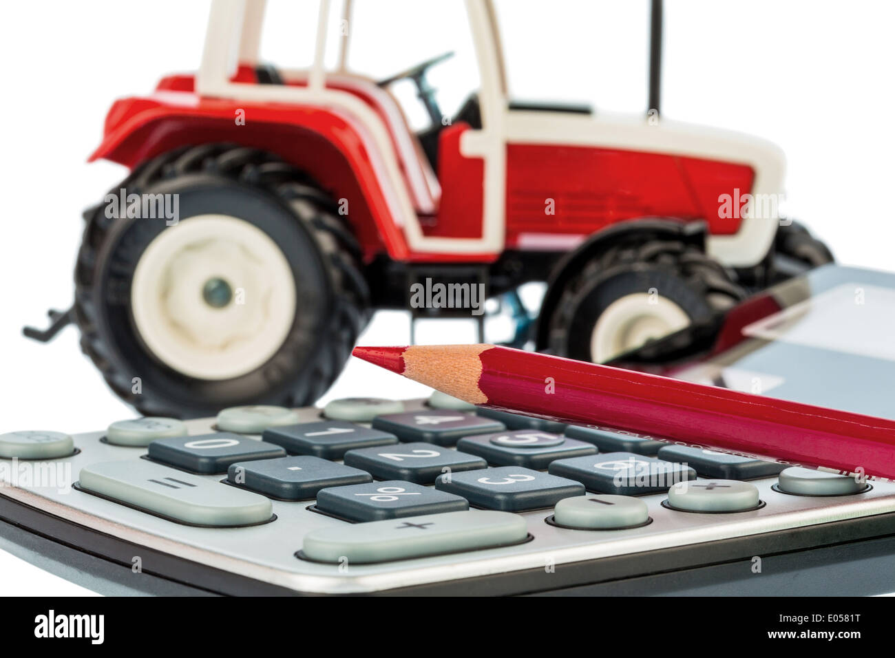 Einen Traktor und einen roten Stift liegt auf einem Taschenrechner. Kosten für Benzin, Abnutzung und Qualitätssicherung. Kosten und unterstützt in der Wirtschaft Stockfoto