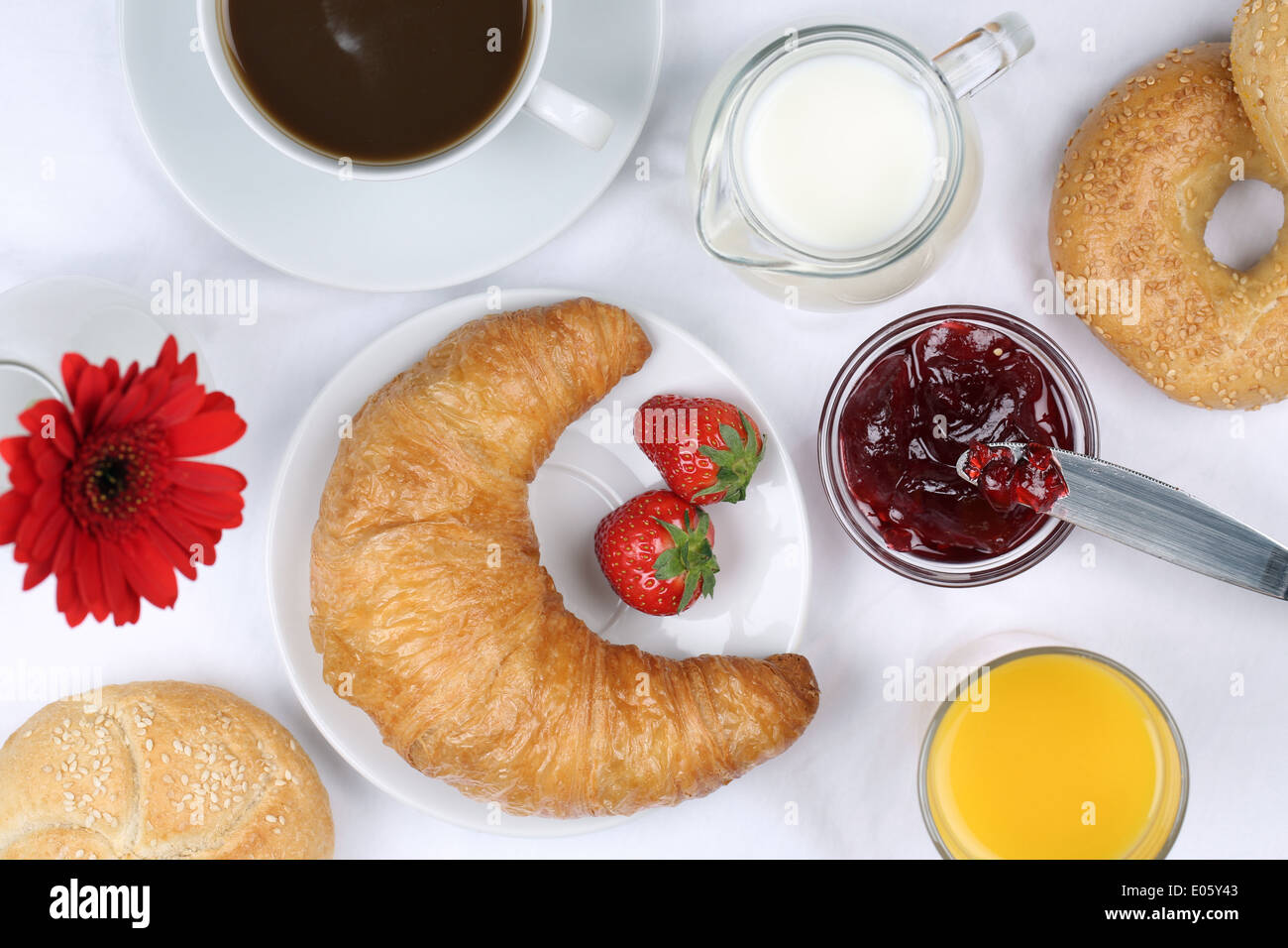 Frühstück mit einem Croissant, Brötchen, Marmelade, Kaffee und Saft von oben Stockfoto