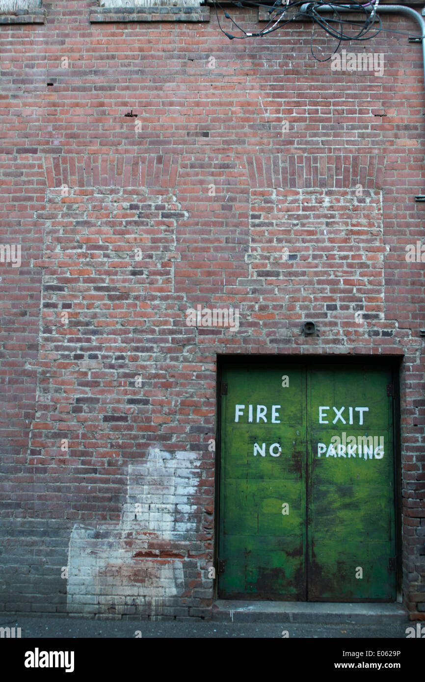 Ein Feuer Ausfahrt Tür in einem gemauerten Gebäude führt zu einer Gasse. Stockfoto