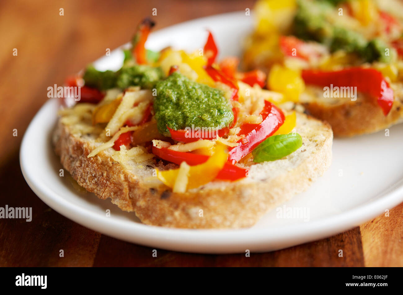 Rote und gelbe Paprikaschote, veganen Käse und hausgemachte Vegan-Basilikum-Pesto auf geröstetem Brot. Stockfoto