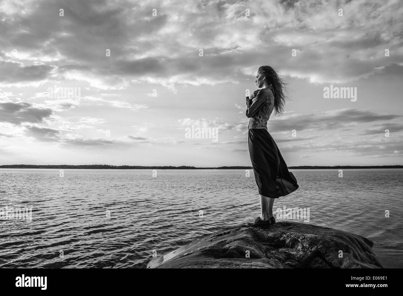 Schöne junge Frau sieht am Horizont am Ufer, der Wind weht und bewölktem Himmel - schwarz / weiß Bild Stockfoto