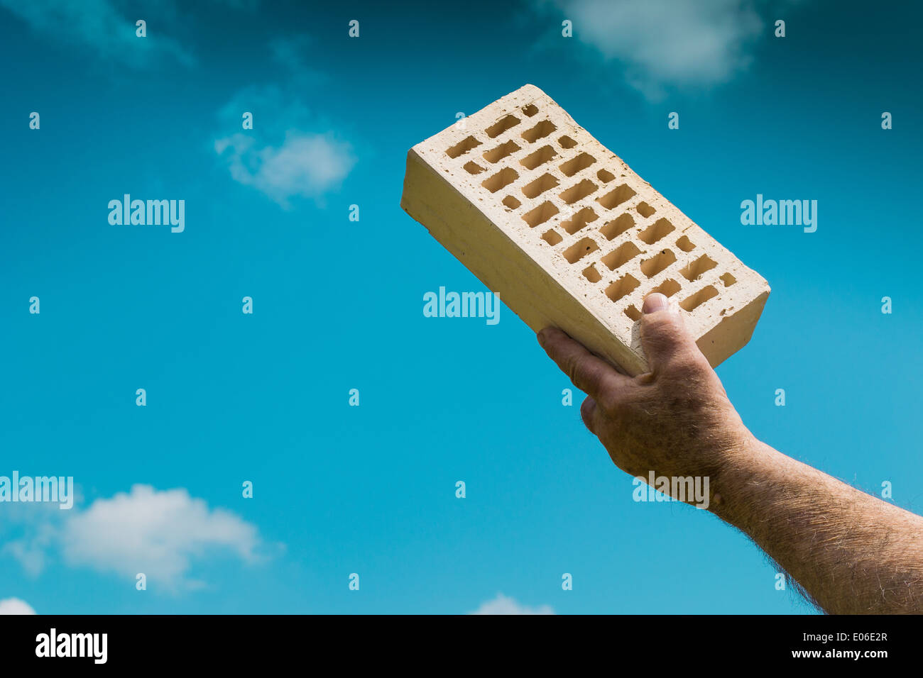 Eines Mannes Hand hält einen Stein gegen den blauen Himmel. Stockfoto
