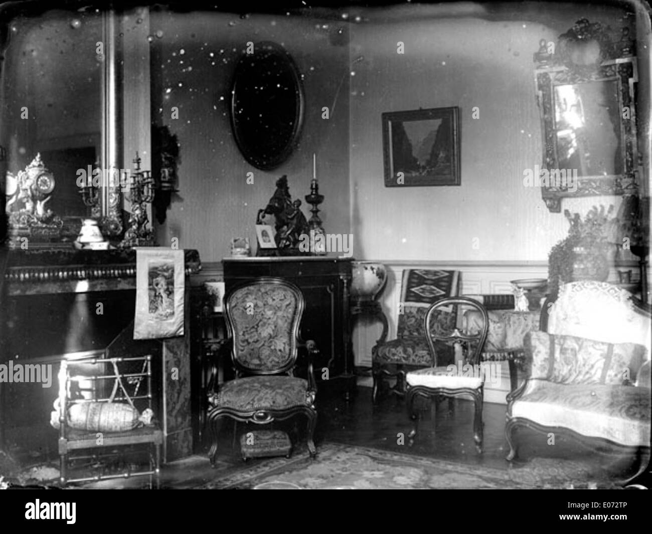 Dieses Gemälde mit dem Titel „Intérieur d'un Salon bourgeois“ zeigt das Innere eines bürgerlichen Wohnzimmers in Deutschland. Das Kunstwerk fängt die feinen Details der Möbel aus dem 19. Jahrhundert und die kulturellen Nuancen der Zeit ein und spiegelt den wohlhabenden Lebensstil wider. Stockfoto