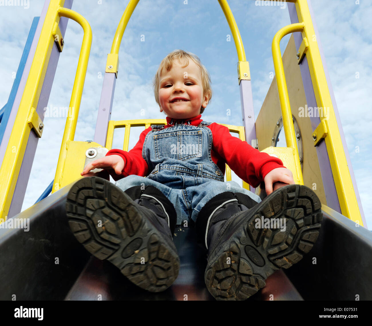 Ein zwei Jahre alter Junge auf einer Folie auf einem Spielplatz spielen Stockfoto