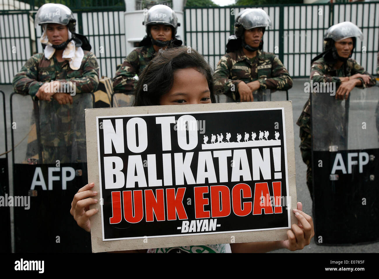 (140505)--QUEZON CITY, 5. Mai 2014 (Xinhua)--ein Aktivist hält ein Plakat vor philippinischen Soldaten während einer Protestkundgebung gegen die verbesserte Verteidigung Zusammenarbeit Vereinbarung (Wi) vor den Toren der Streitkräfte der Philippinen (AFP)-zentrale am Camp Aguinaldo in Quezon City, Philippinen, 5. Mai 2014. Die Aktivisten verurteilen die Wi, wobei die USA haben eine erhöhte Drehzahl Präsenz auf den Philippinen und haben besseren Zugang zu Häfen, Flugplätze und Militärbasen des Landes. Die Demonstranten protestieren auch gegen das Balikatan 2014, wh Stockfoto