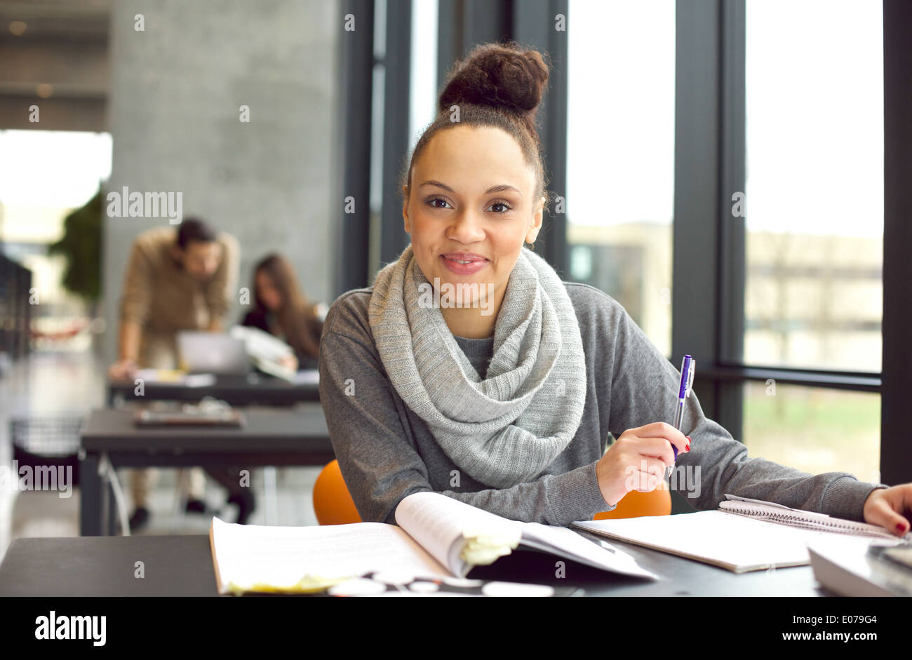 Überzeugt junge Studentin studiert. Frau sitzt am Schreibtisch mit Büchern. Stockfoto