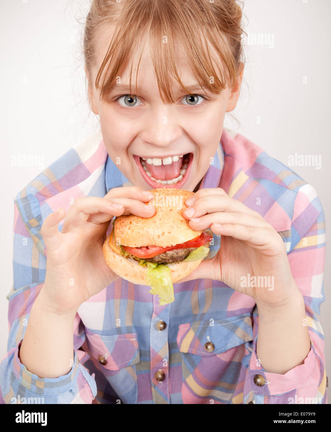 Kleine blonde lächelndes Mädchen isst Hamburger über weiße Wand Stockfoto