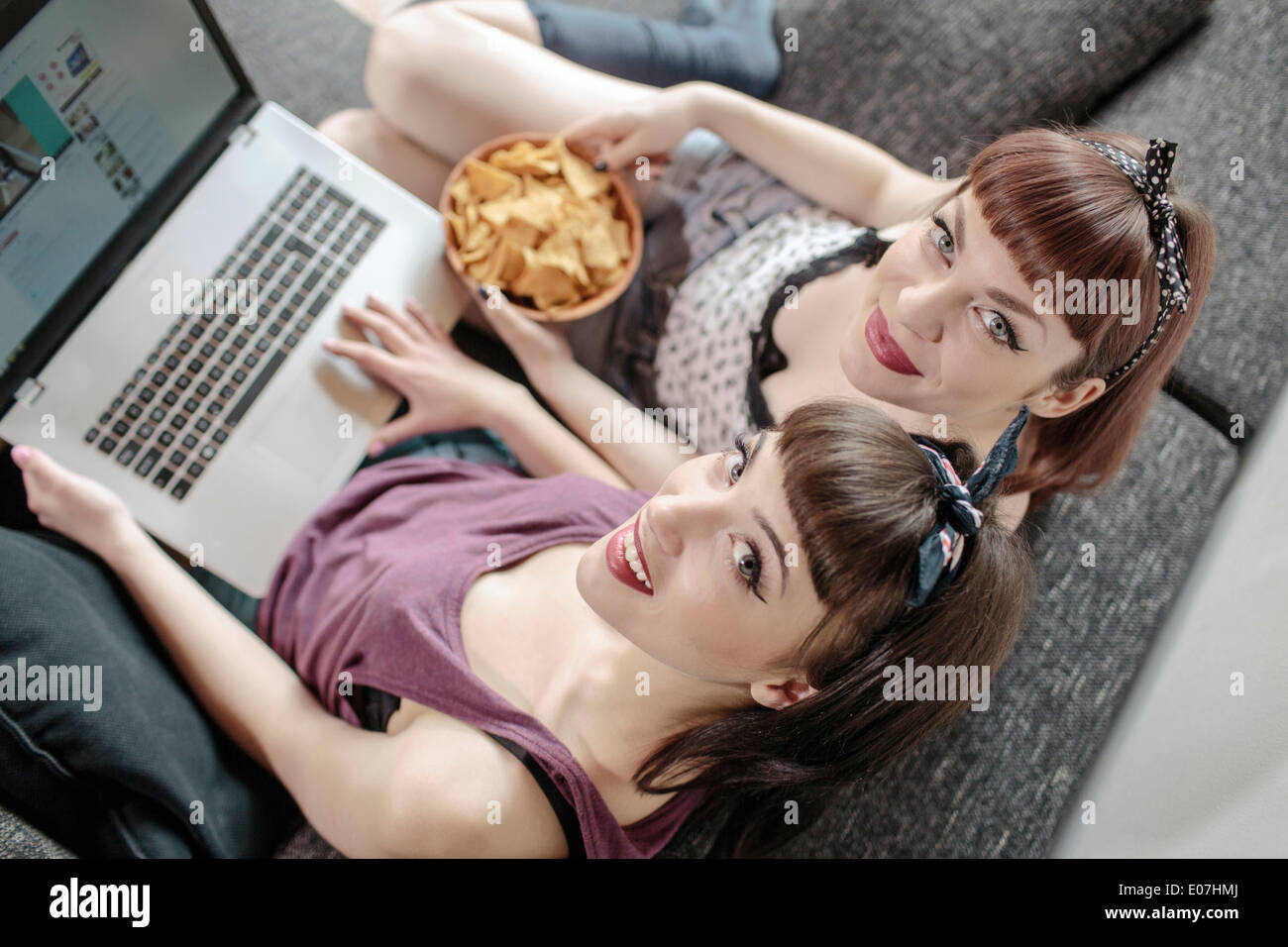 Zwei junge Frauen, die das Surfen im Netz und einen Snack Stockfoto