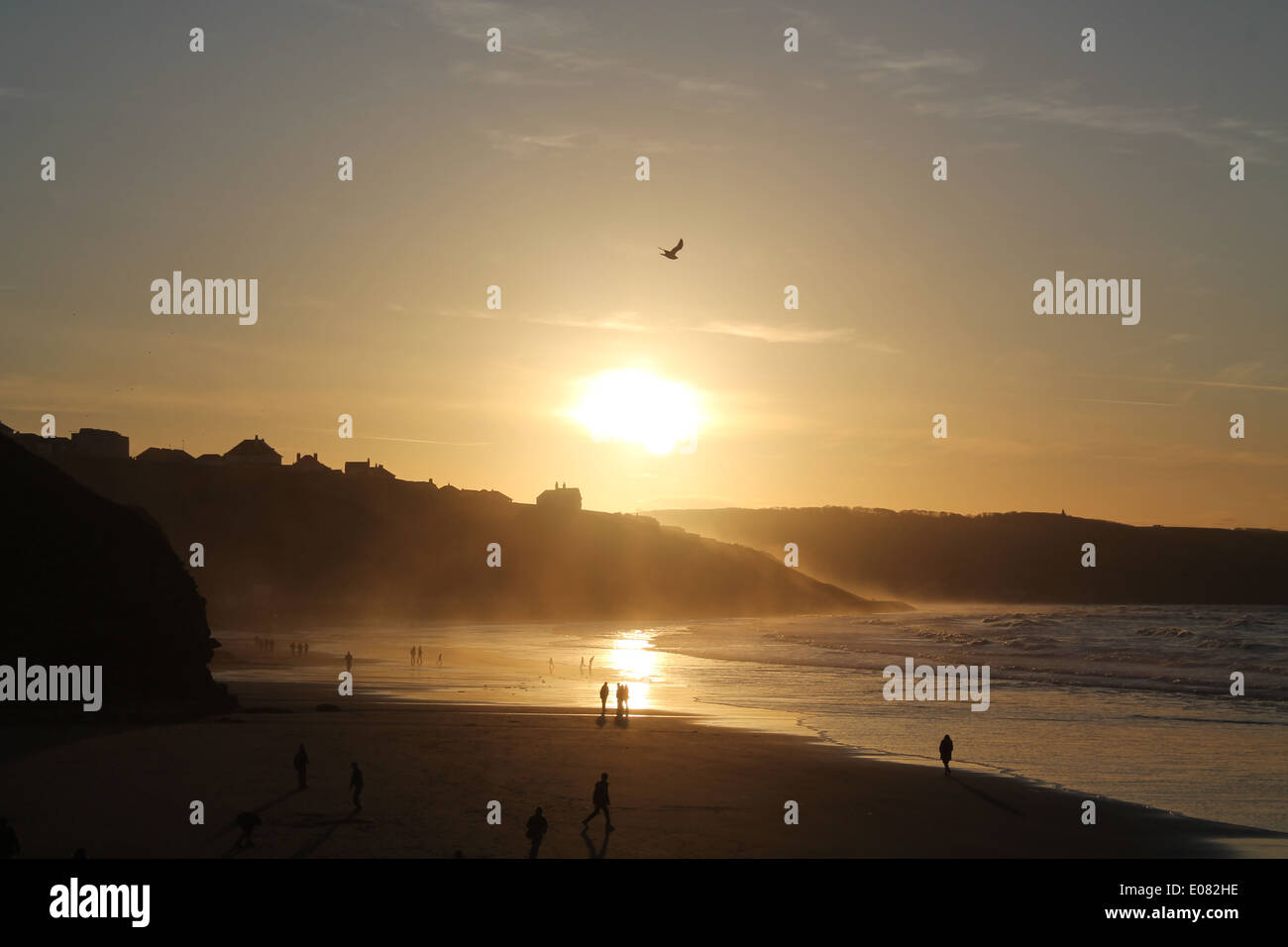 Tiefstehende Sonne funkelt am Rand Wassers, wie die Sonne über Silhouette Landzungen hinter Whitby Strand Stockfoto