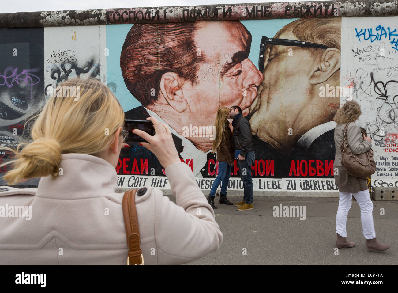 Ein paar Kuss vor Dimitry Vrubel Gemälde auf der Berliner Mauer von Leonid Brezhnev und Erich Honecker Stockfoto
