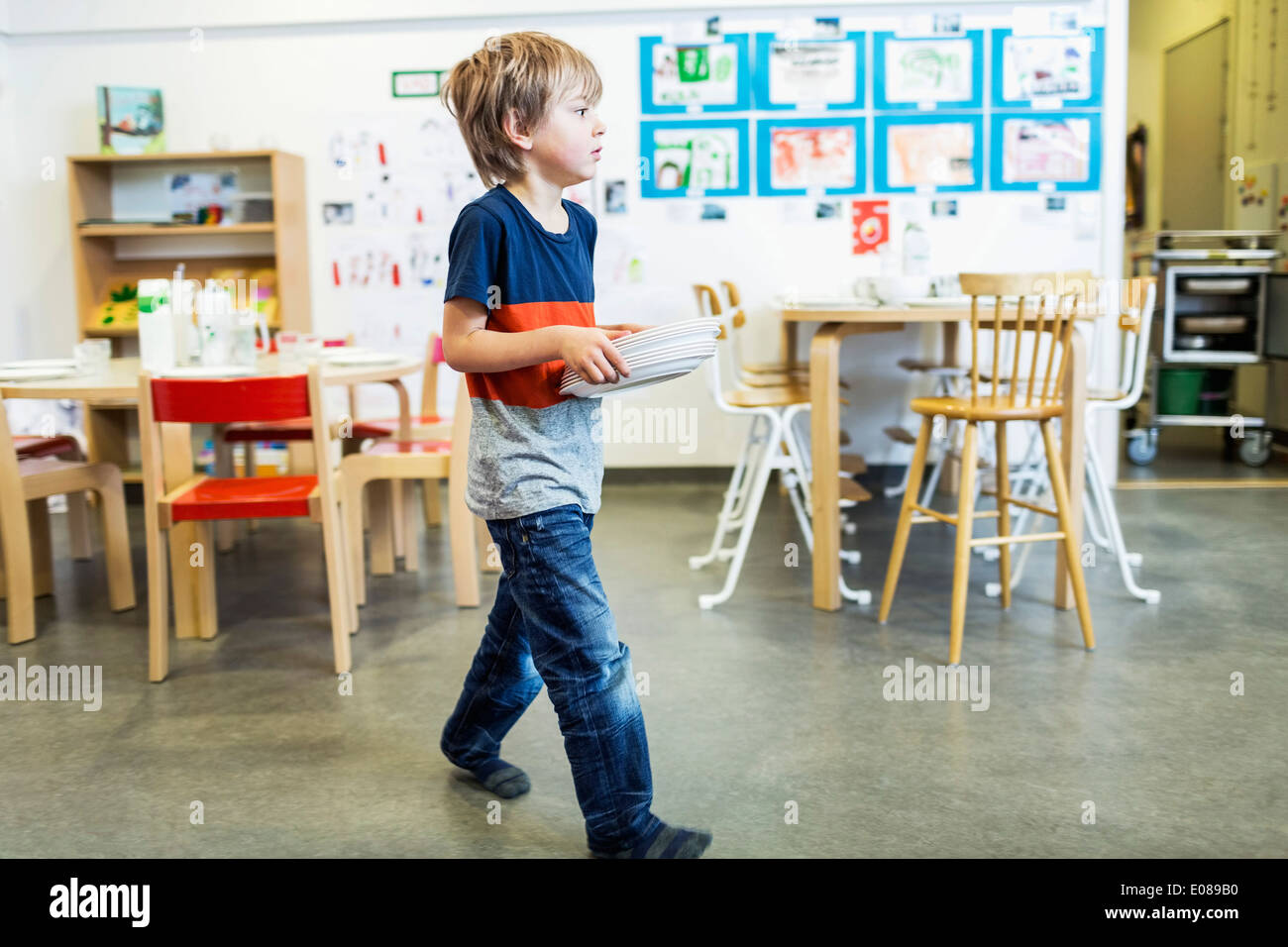 Elementare junge tragen Platten im kindergarten Stockfoto