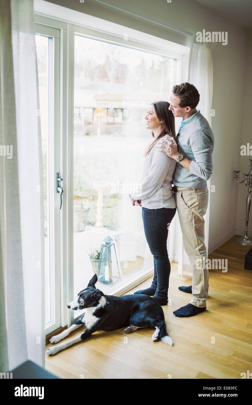 Seitenansicht des Paares Blick durch Fenster zu Hause Stockfoto