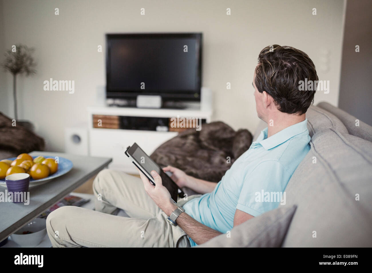 Seitenansicht des Mannes mit digital-Tablette auf Sofa zu Hause sitzen Stockfoto